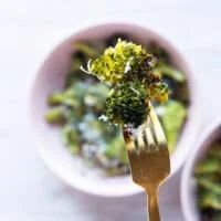 A fork holding an air fryer broccoli piece close up showing the crisp and perfectly cooked broccoli