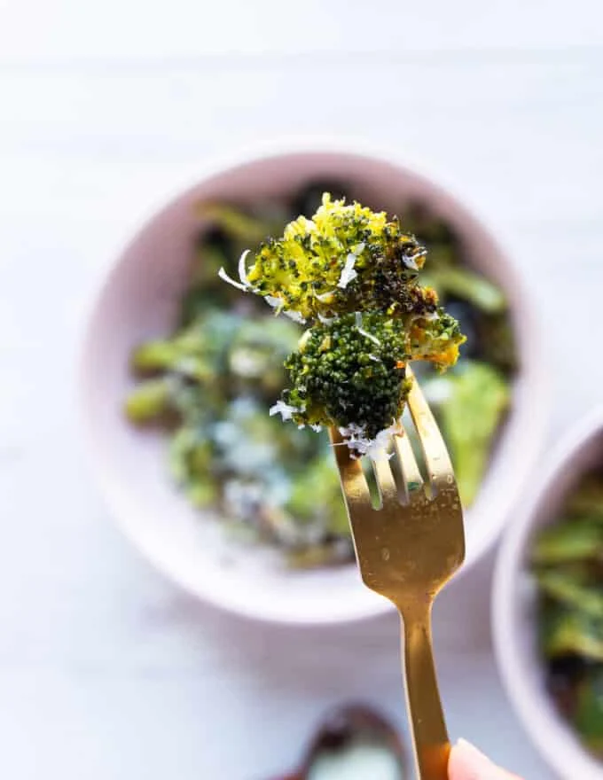 A fork holding an air fryer broccoli piece close up showing the crisp and perfectly cooked broccoli