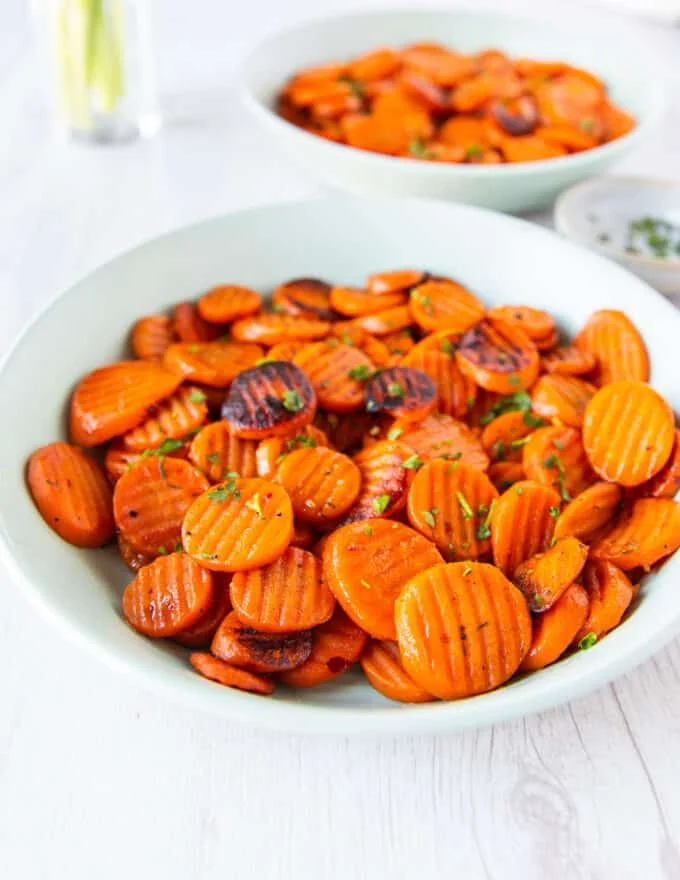 maple glazed carrots served on a plate with fresh herbs