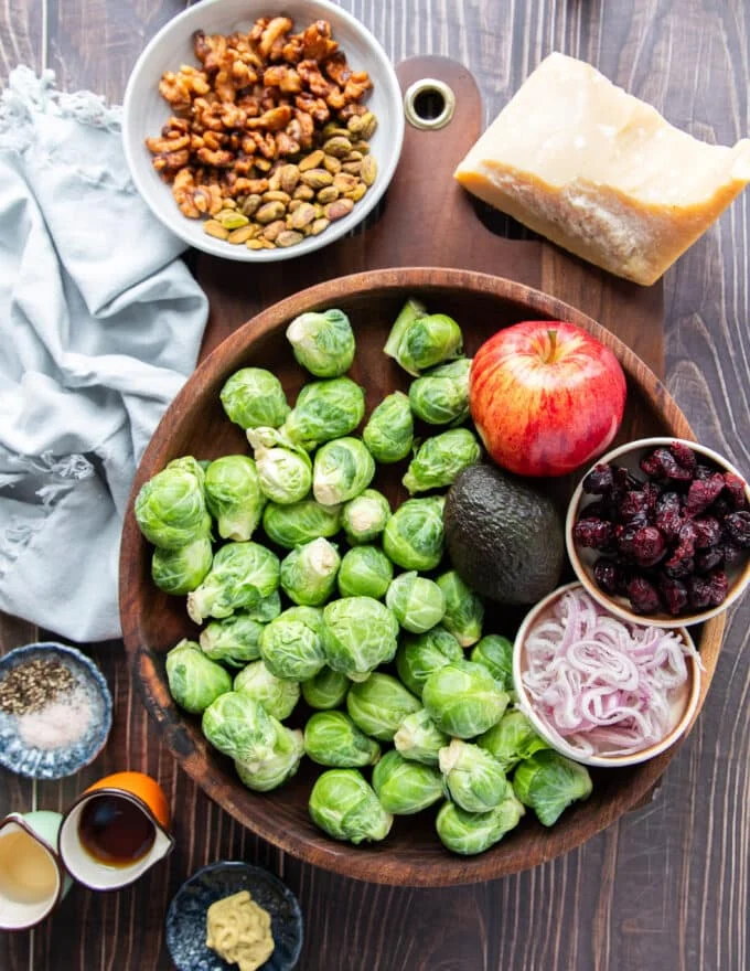 Ingredients needed to make brussel sprout salad including all ingredients in small bowls