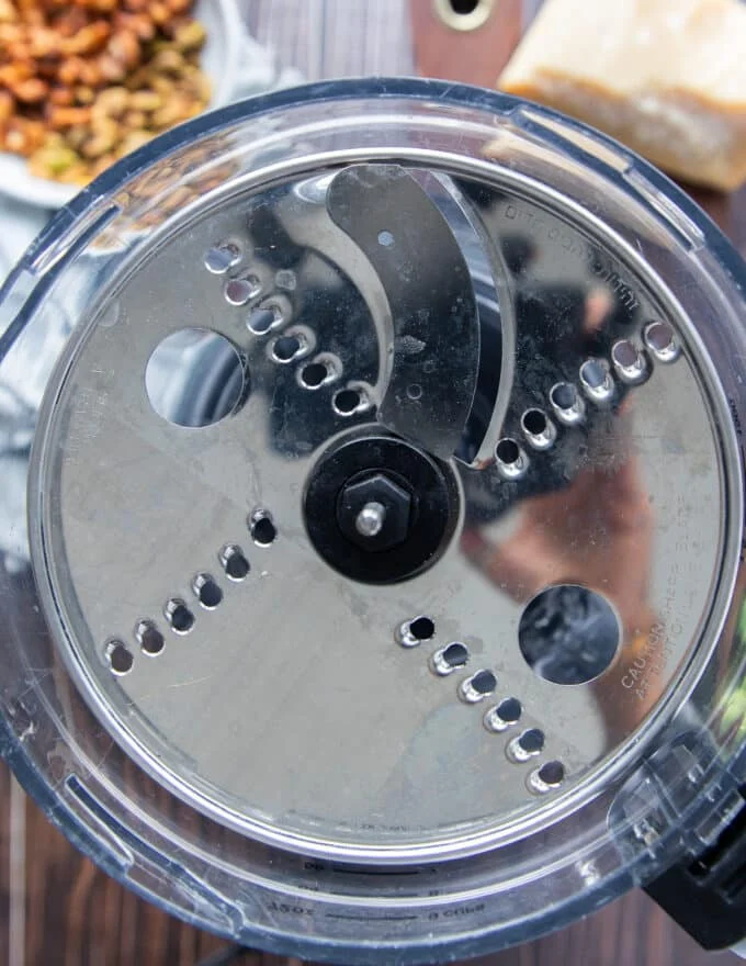 A blade of a food processor set up to shred the brussel sprouts