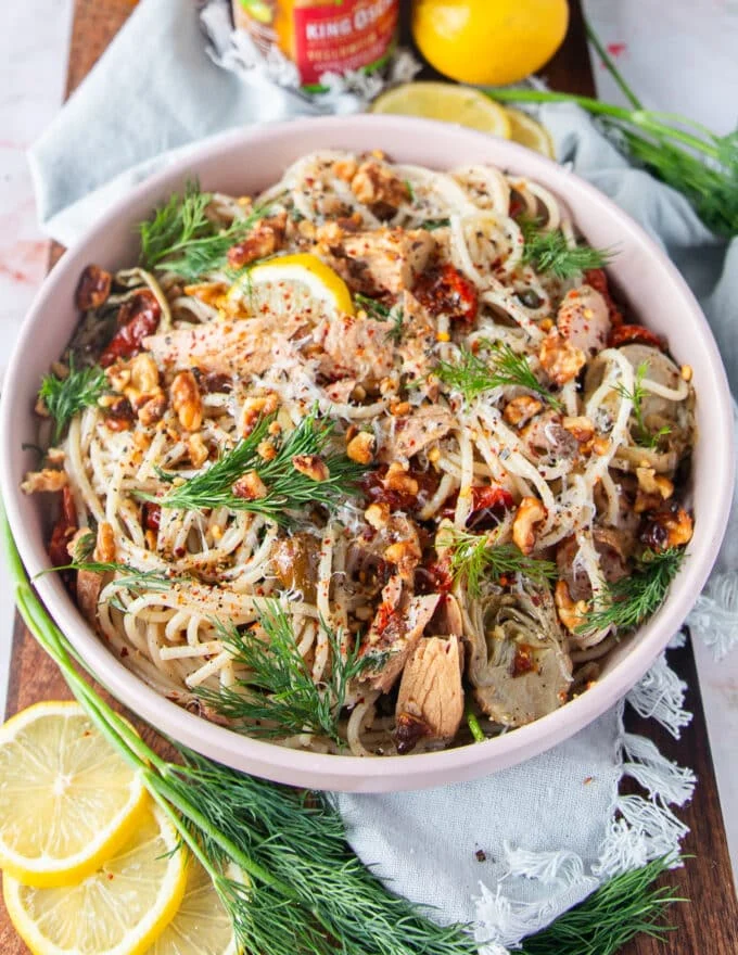 close up of tuna pasta bowl with herbs, capers, sun dried tomato, tuna chunks and parmesan cheese