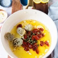sun dried tomato, capers and artichokes are added to the sliced garlic once it's toasted in the saucepan
