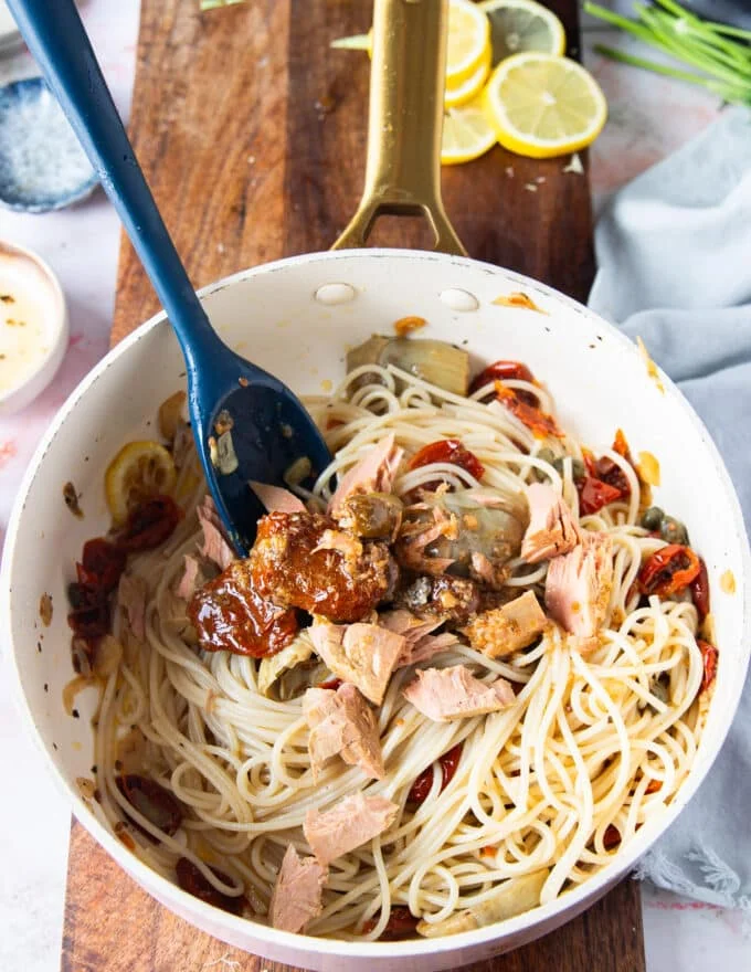cooked pasta and tuna chunks are added to the sauce pan