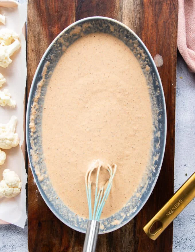 water is added and the batter is ready in a shallow bowl to make buffalo cauliflower bites