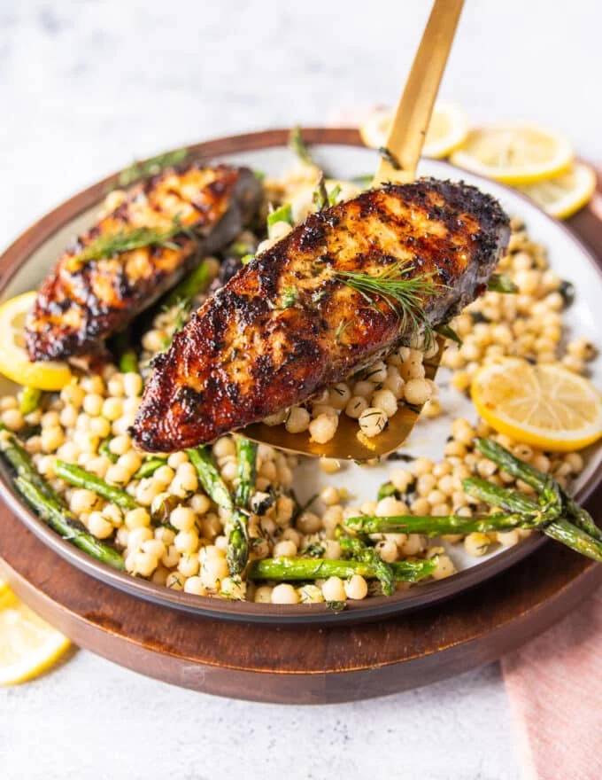 A spatula holding close up a cooked kingfish steak showing the golden grill mark on the fish