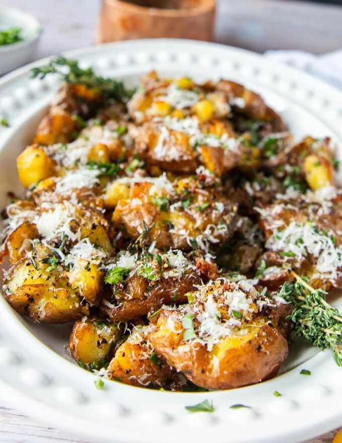 smashed potatoes on a serving plate close up showing the fluffy inside and crisp outside