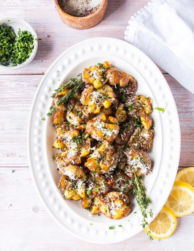 A plate of smashed potatoes with parmesan and herbs