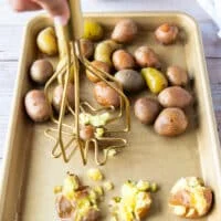 A masher used to smash the potatoes one at a time on the baking sheet
