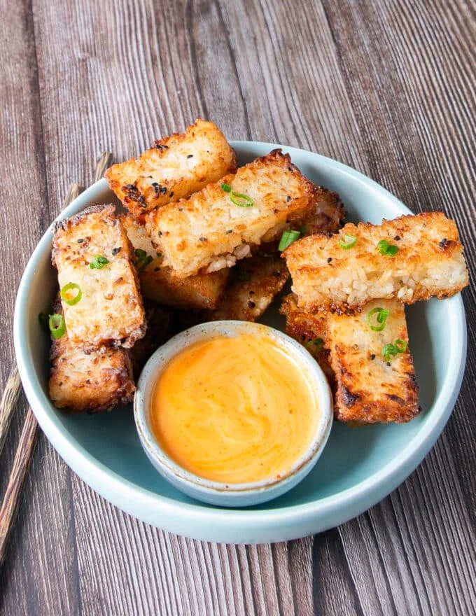 A plate of crispy rice stacked over each other with a bowl of spicy mayo