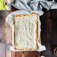 A hand Spreading the sauce over the bottom and tops of the slider bread