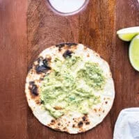 charred tortilla with a spread of poblano sauce and taco sauce