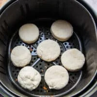 biscuits arranged in an air fryer basket in a single layer spaced apart