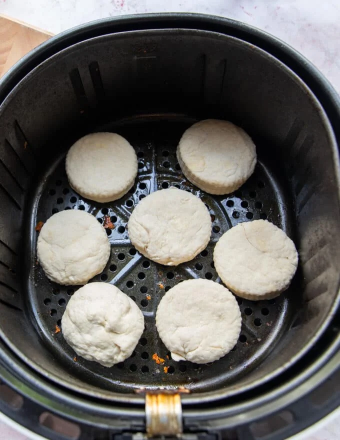 biscuits arranged in an air fryer basket in a single layer spaced apart