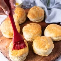 A brush brushing melted butter over the warm biscuits right out of the air fryer