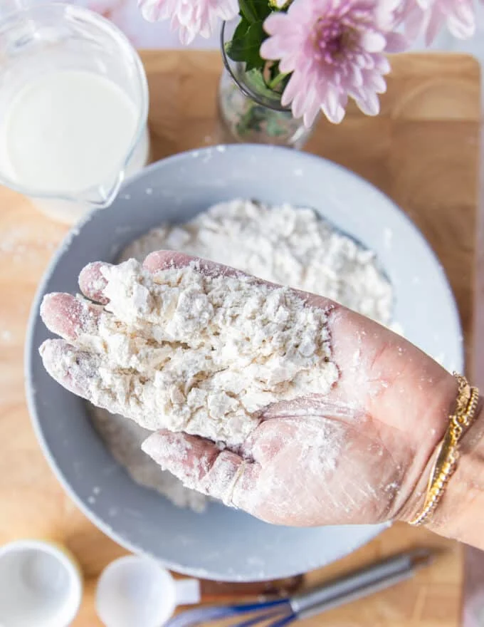 A hand holding the butter incorporated into the flour showing the coarse crumb texture ready to add the buttermilk