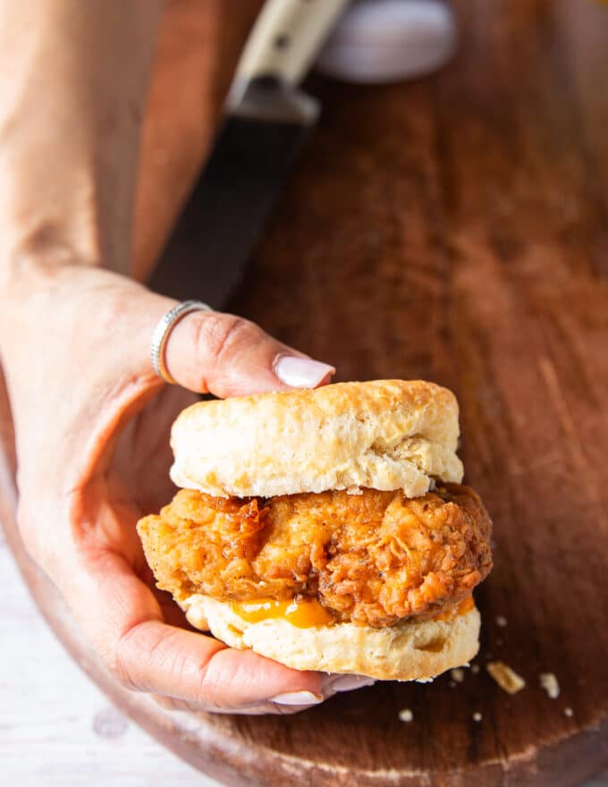 A hand holding a chicken biscuit close up showing the textures and layers