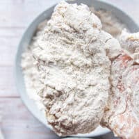 The final thick coating of flour is added to the chicken before frying