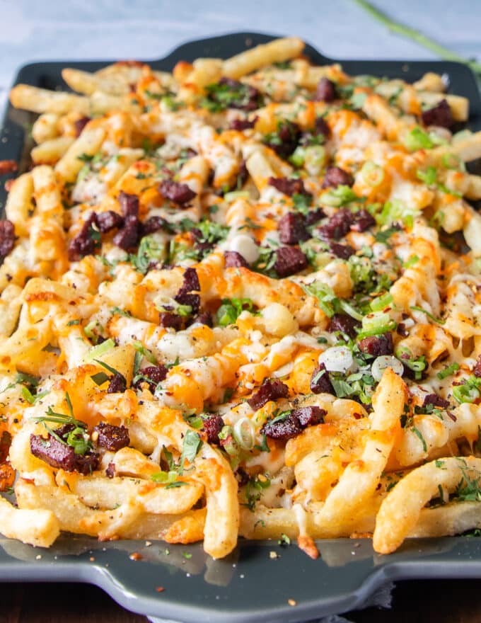 side view of loaded fries tray with cheese, sauce and toppings