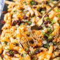 A fork pulling some cheese fries showing the cheese pull and all the toppings on top