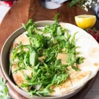 building a sardines bowl starts with a layer of bread and then some arugula on top