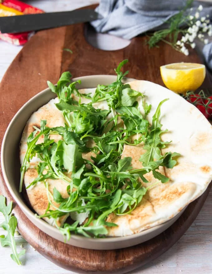 building a sardines bowl starts with a layer of bread and then some arugula on top