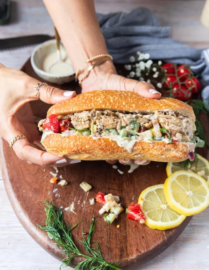 two hands holding a finished sardine sandwich fully assembled and ready to enjoy showing the layers