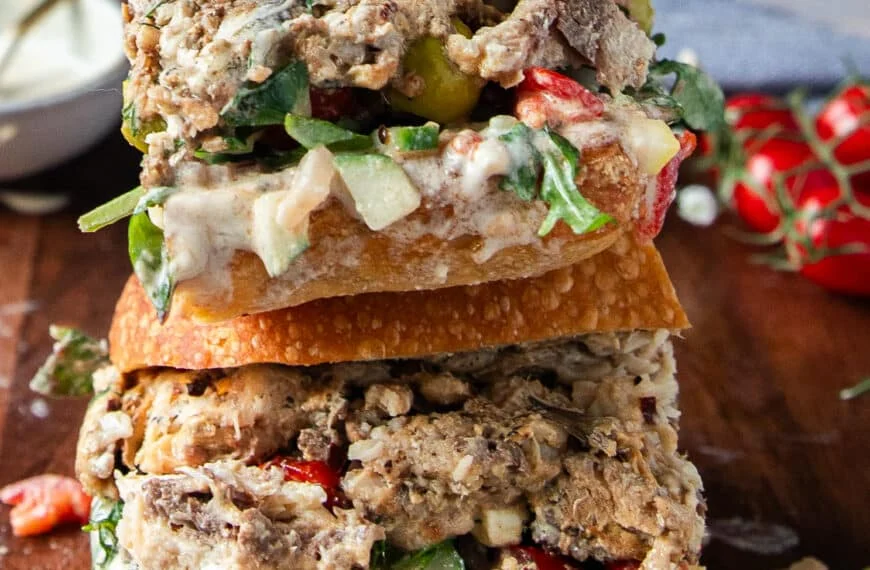 Cut up sardine sandwich in half close up shwoing the layers of sardines and fresh ingredients stuffed inside the sandwich bread