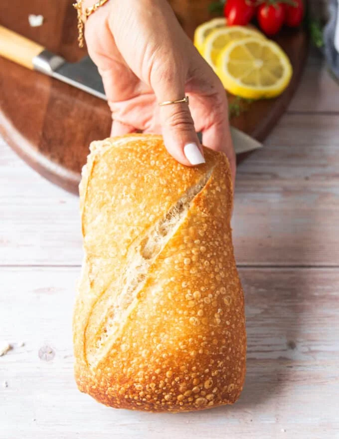 A hand holding a rustic ciabatta bread ready to toast it for maximum crunch on the sandwich