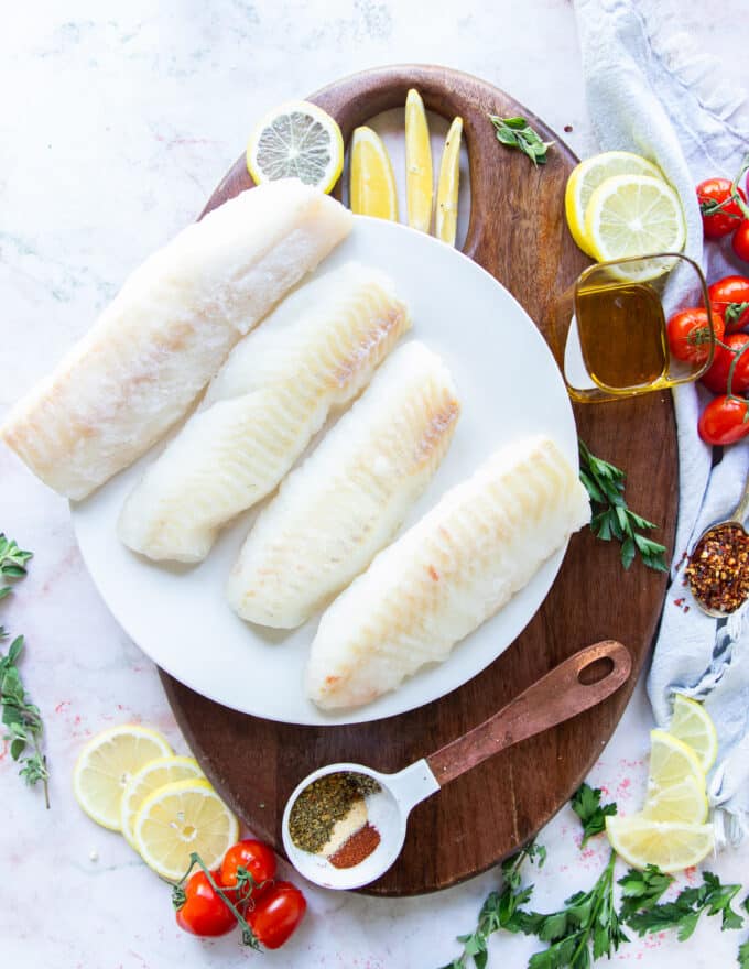 Ingredients to make air fryer cod on a wooden board