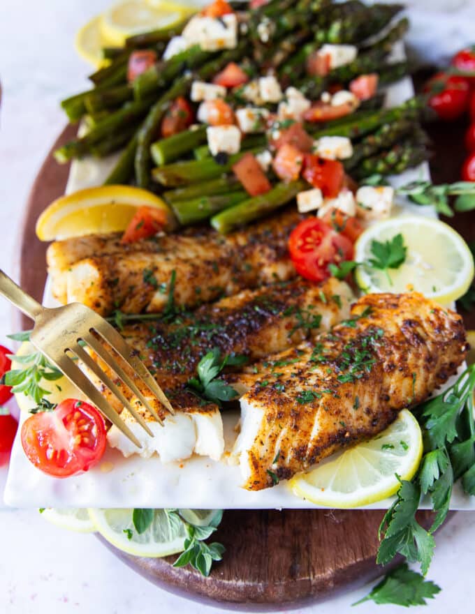 A fork flaking succulent air fryer cod showing how perfectly cooked in the air fryer