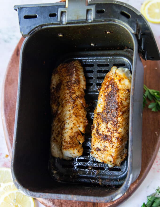 Perfect cooked air fryer cod in the air fryer basket.