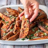 A hand holding a potato wedge close up showing how crispy the outside is and showing off the bold seasoning