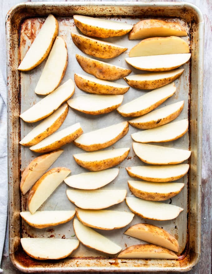 Potatoes washed and cut into wedges, laying on a baking sheet