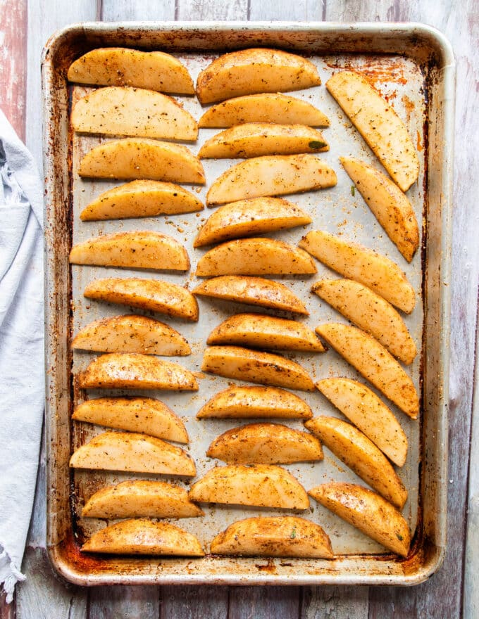 Seasoned potato wedges on a baking sheet in a single layer and ready to bake