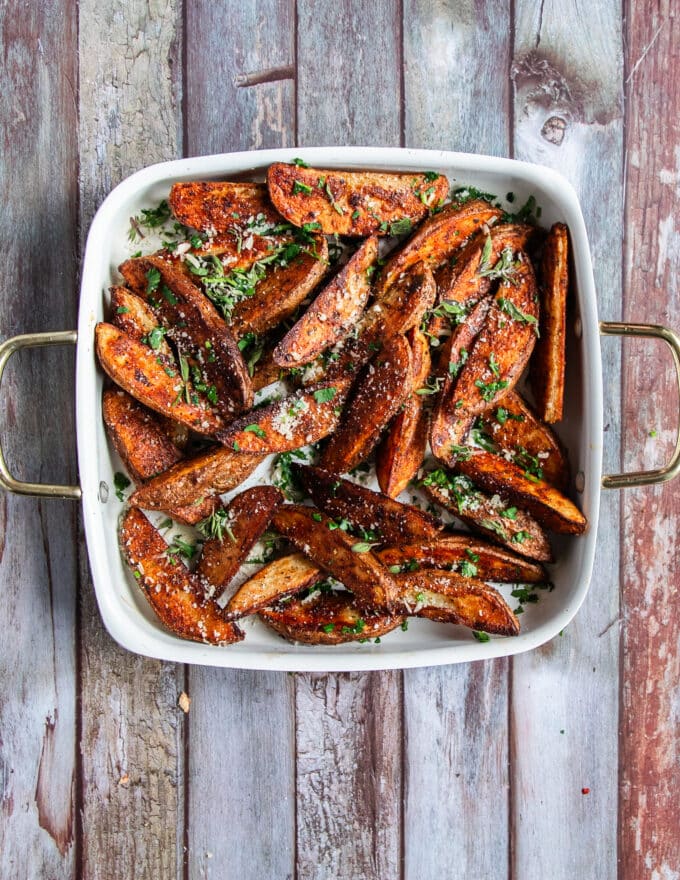 top view of a finished plate of potato wedges finished with parmesan cheese and some parsley
