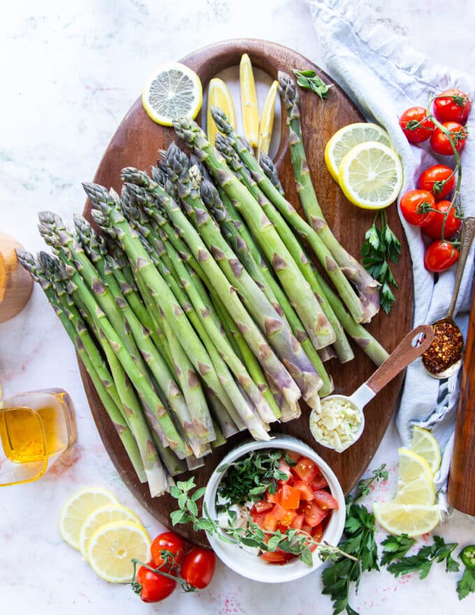 Ingredients to make baked asparagus on a board