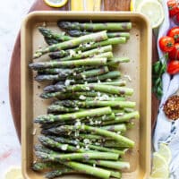 Asparagus arranged on a baking sheet in a single layer and seasoned with olive oil, garlic and seasoning