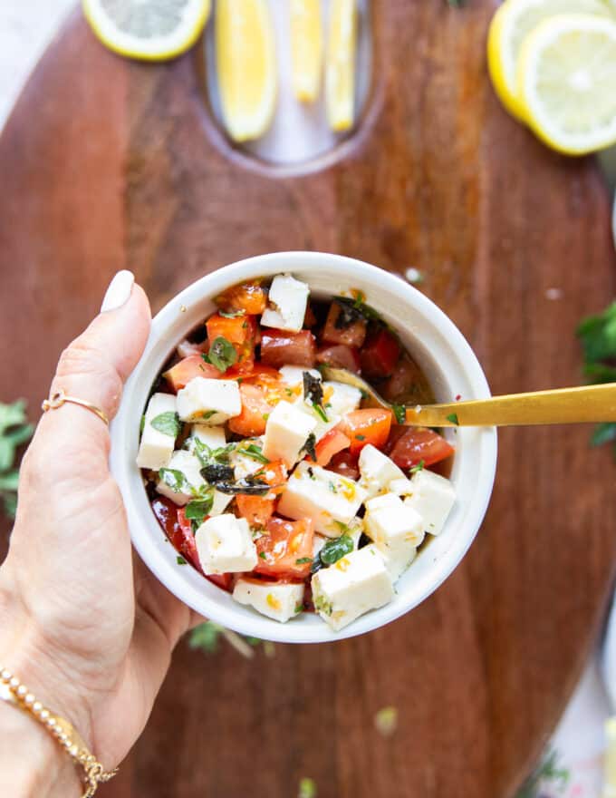 A bowl of feta, tomatoes, herbs, lemon juice and olive oil mixed and ready to finish the baked asparagus