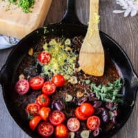 tomatoes, lemon zest and herbs, olives are added to the pan