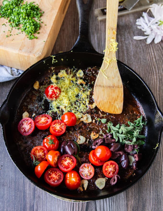 tomatoes, lemon zest and herbs, olives are added to the pan